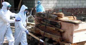 The body of a paramilitary soldier who died due to Covid-19 pandemic being cremated as son being consoled by the security personnel in protection suits in Srinagar on Tuesday